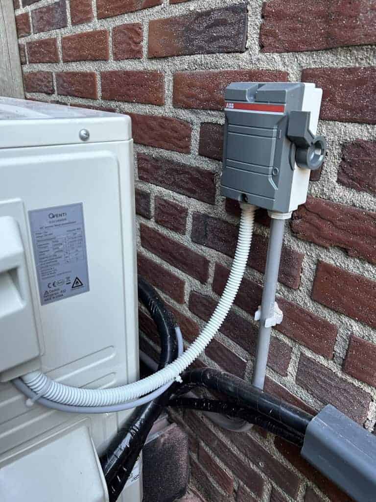Energiemeter en kabels aan buitenmuur.